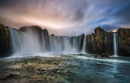 A breathtaking view of Goðafoss waterfall in Akureyri, Iceland, showcasing stunning natural beauty with flowing water against a dramatic sky. 4K Ultra HD desktop wallpaper.