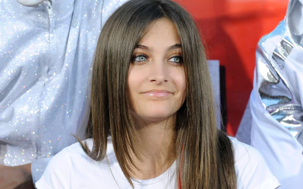 HD PC desktop wallpaper featuring celebrity Paris Jackson with long straight hair and a subtle smile against a vibrant red and white background.