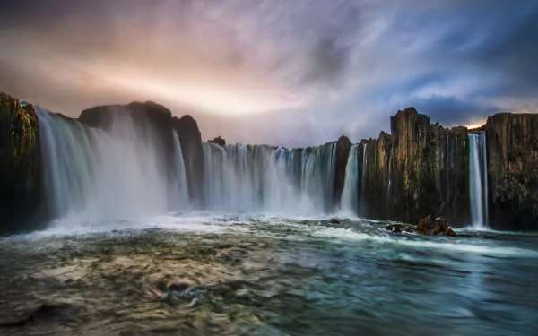 A breathtaking view of Goðafoss waterfall in Akureyri, Iceland, showcasing stunning natural beauty with flowing water against a dramatic sky. 4K Ultra HD desktop wallpaper.