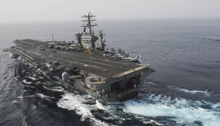 Aerial view of the USS Nimitz (CVN-68), a military aircraft carrier, navigating through the ocean, showcasing its impressive size and capabilities.