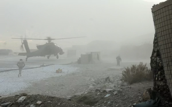 2K Quad HD PC desktop wallpaper of a Boeing AH-64 Apache kicking up dust over a military landing zone with soldiers nearby.