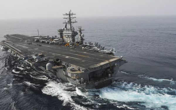 Aerial view of the USS Nimitz (CVN-68), a military aircraft carrier, navigating through the ocean, showcasing its impressive size and capabilities.