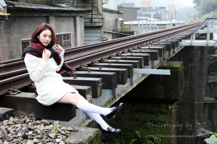 A Taiwanese woman model, Lín Yǔ, sits on railroad tracks wearing a white coat and black shoes, captured in an HD PC desktop wallpaper background.