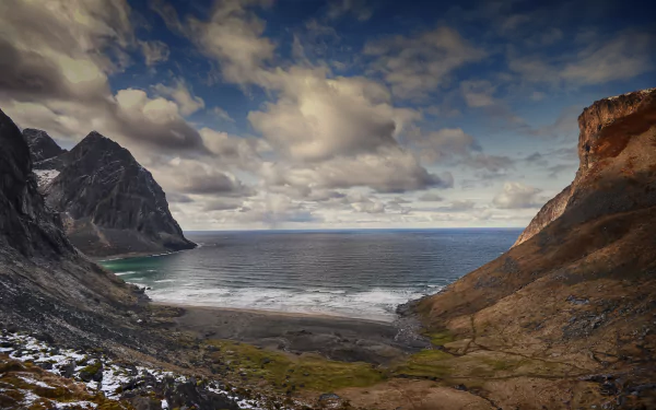 A stunning seascape of Kvalvika Beach in the Lofoten Islands, Norway, showcasing dramatic cliffs, gentle waves, and a vibrant sky, captured in rich 4K Ultra HD detail.