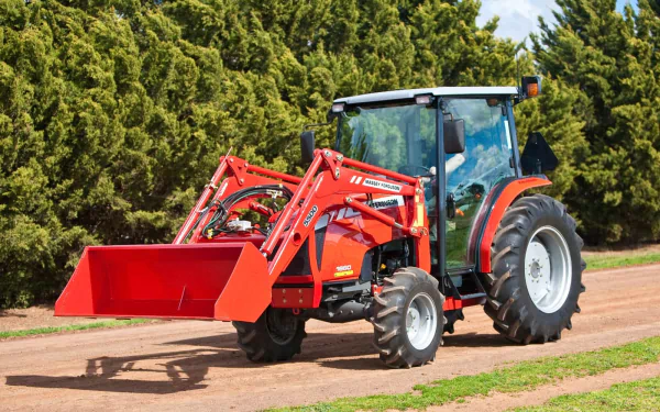 A vibrant Massey Ferguson tractor driving on a dirt road, surrounded by lush green trees, showcased as a high-definition desktop wallpaper and background.