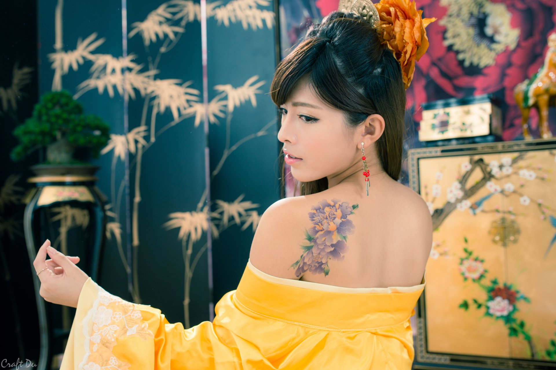 5K Ultra HD desktop wallpaper: portrait of a Taiwanese Asian woman in a yellow traditional costume with ornate hair-dress and dangling earrings, revealing a floral shoulder tattoo.