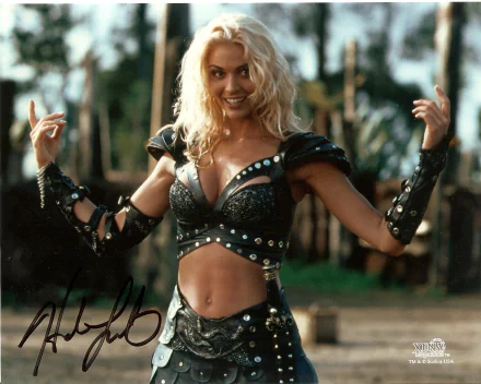 HD desktop wallpaper featuring a character from the TV show Xena: Warrior Princess, dressed in warrior attire with a confident smile and raised arms.