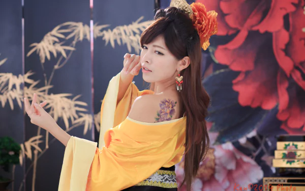 Woman in yellow traditional costume with ornate hair-dress, dangling earrings and a floral shoulder tattoo, captured in vibrant 5K Ultra HD desktop wallpaper.