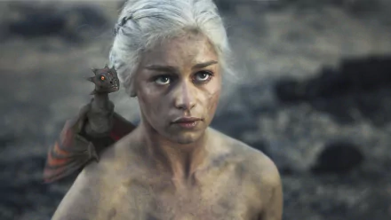 HD desktop wallpaper featuring Emilia Clarke as Daenerys Targaryen from Game of Thrones, with a small dragon on her shoulder in a barren landscape.