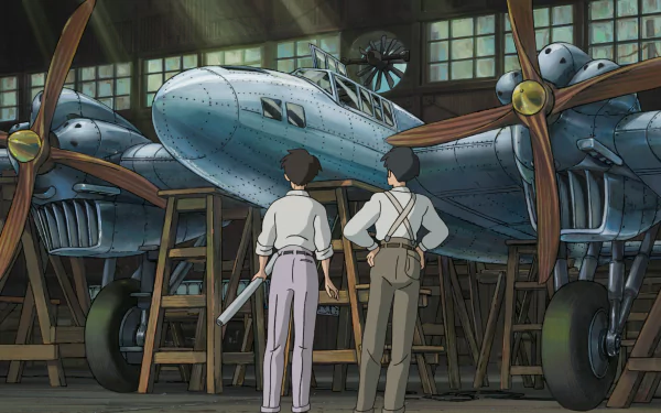 HD wallpaper of two characters from The Wind Rises standing in front of a vintage airplane inside a hangar.