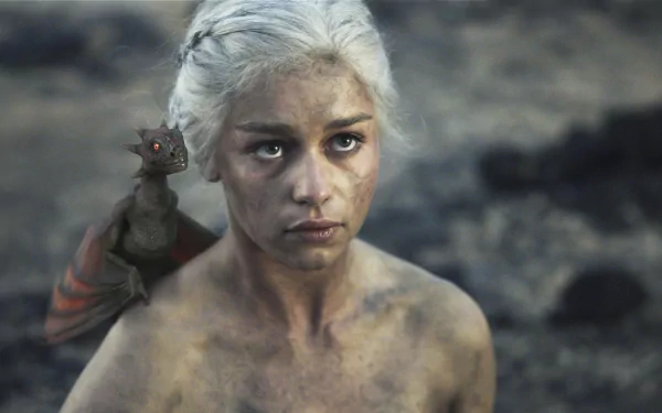 HD desktop wallpaper featuring Emilia Clarke as Daenerys Targaryen from Game of Thrones, with a small dragon on her shoulder in a barren landscape.
