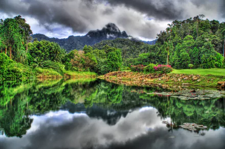A serene view of Langkawi Island, Malaysia, showcasing a foggy jungle landscape reflected in tranquil waters, captured in vibrant HDR detail.