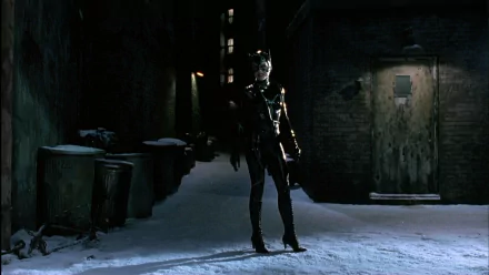 HD PC desktop wallpaper: Catwoman from Batman Returns stands in a snowy, dimly lit alley in a stitched black suit and mask, a single light casting a long shadow.
