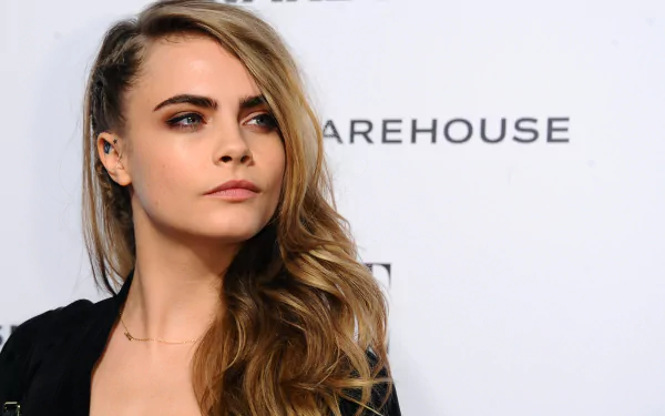 HD desktop wallpaper featuring blonde English actress and model Cara Delevingne with wavy hair and a confident expression at a celebrity event.