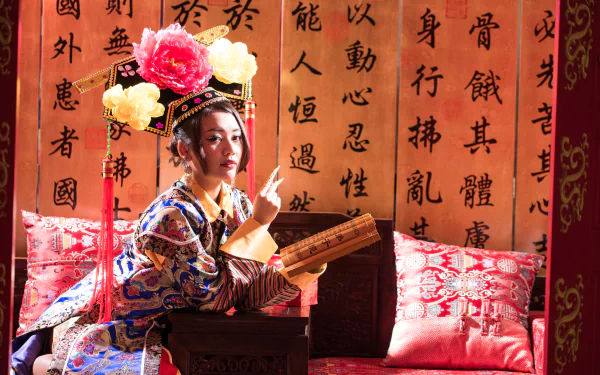 A Taiwanese woman dressed in traditional Chinese costume, holding a scroll, posed against a backdrop of calligraphy in a 4K Ultra HD desktop wallpaper.