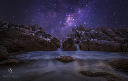 A breathtaking starry night over Australia, featuring the Milky Way illuminating rocky landscapes and serene waters, captured in stunning 4K Ultra HD for a captivating desktop background.