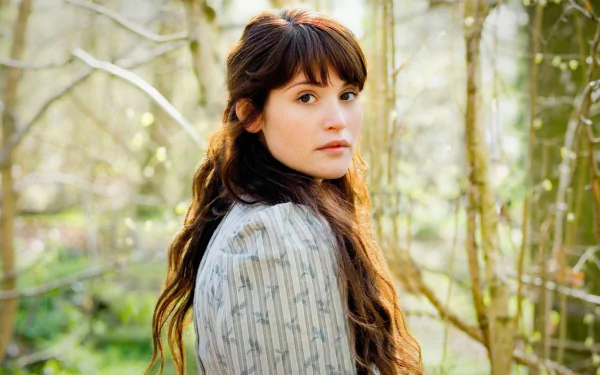 A captivating HD wallpaper featuring Gemma Arterton in a serene forest setting, showcasing her beauty against a backdrop of soft, natural light.