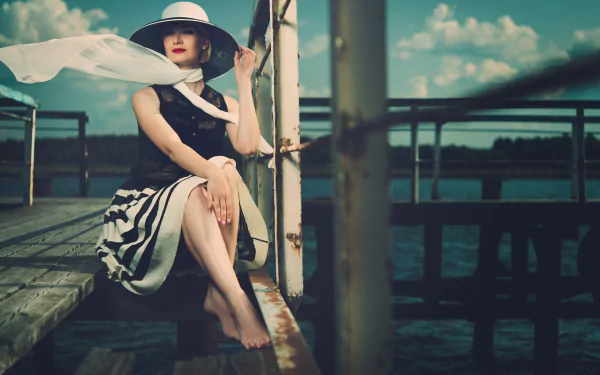 A vintage-style woman in a wide-brim hat and striped skirt sits barefoot on a dock against a serene sky, captured in 4K Ultra HD for PC desktop wallpaper.