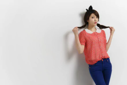 HD desktop wallpaper featuring an Asian woman with plaited hair and cat ears, wearing a red shirt with white polka dots and blue pants, posing against a plain white background.