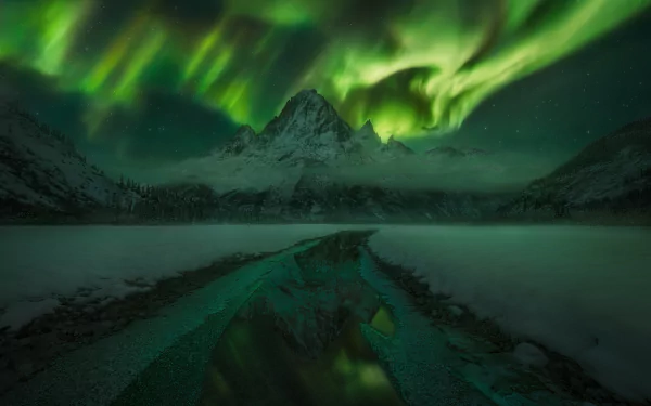 Nighttime landscape of Alaska’s icy mountains under a vivid green aurora borealis sky, captured in high-definition for a stunning desktop wallpaper background.