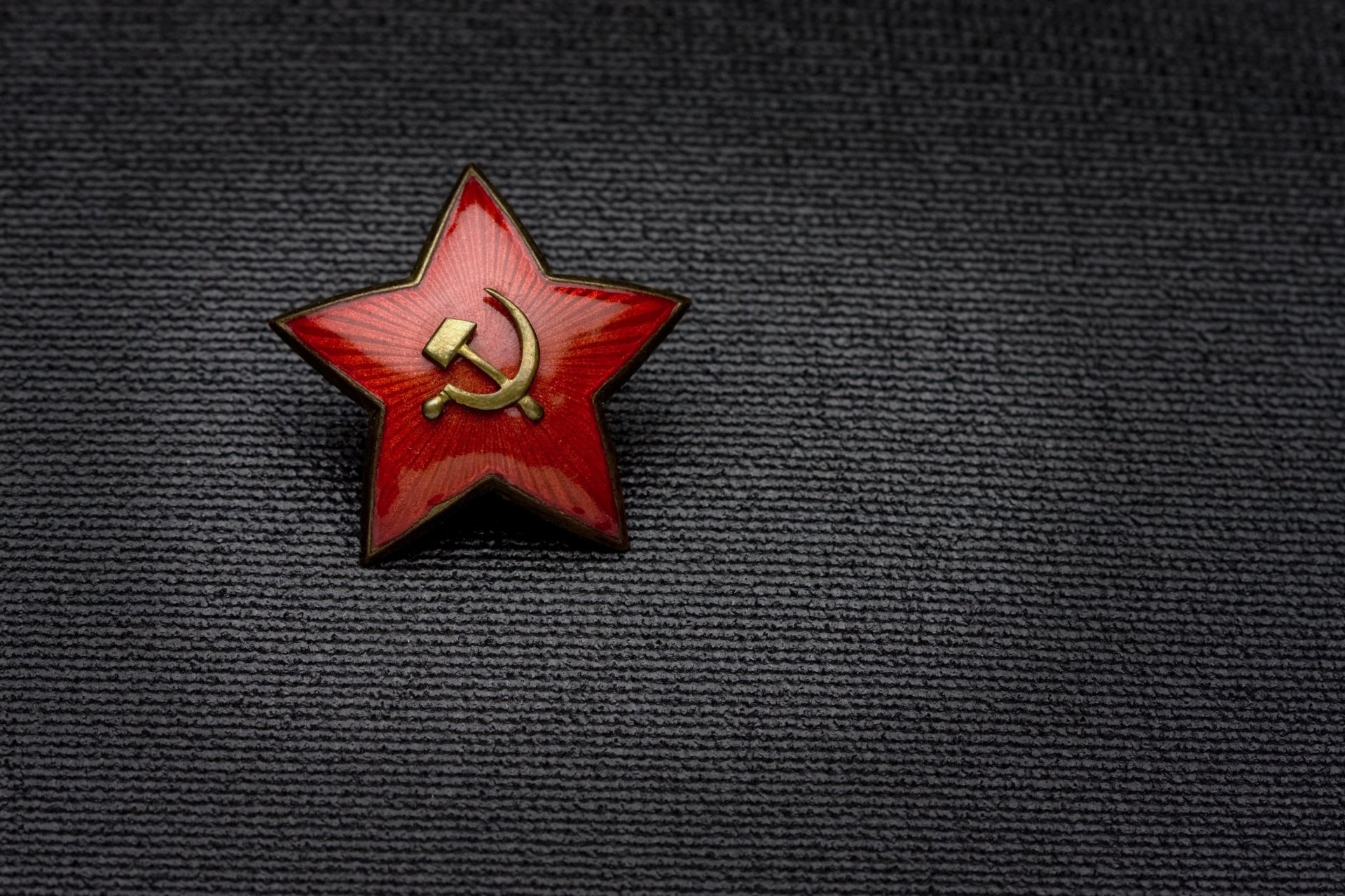 A red star emblem featuring the hammer and sickle, symbolizing the USSR and commemorating Victory Day (9 May), set against a textured dark background in 4K Ultra HD.