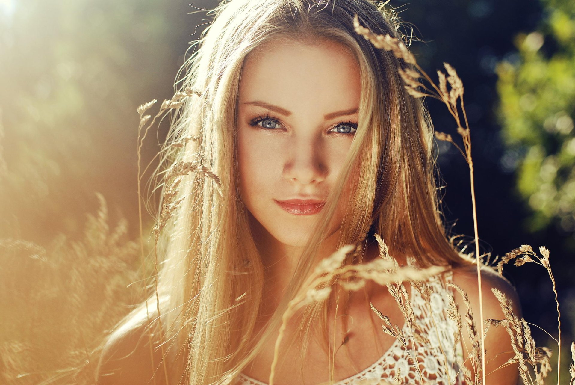 A sunny HD desktop wallpaper featuring a blonde woman with blue eyes, set against a backdrop of plants and natural light, providing a serene and bright background.