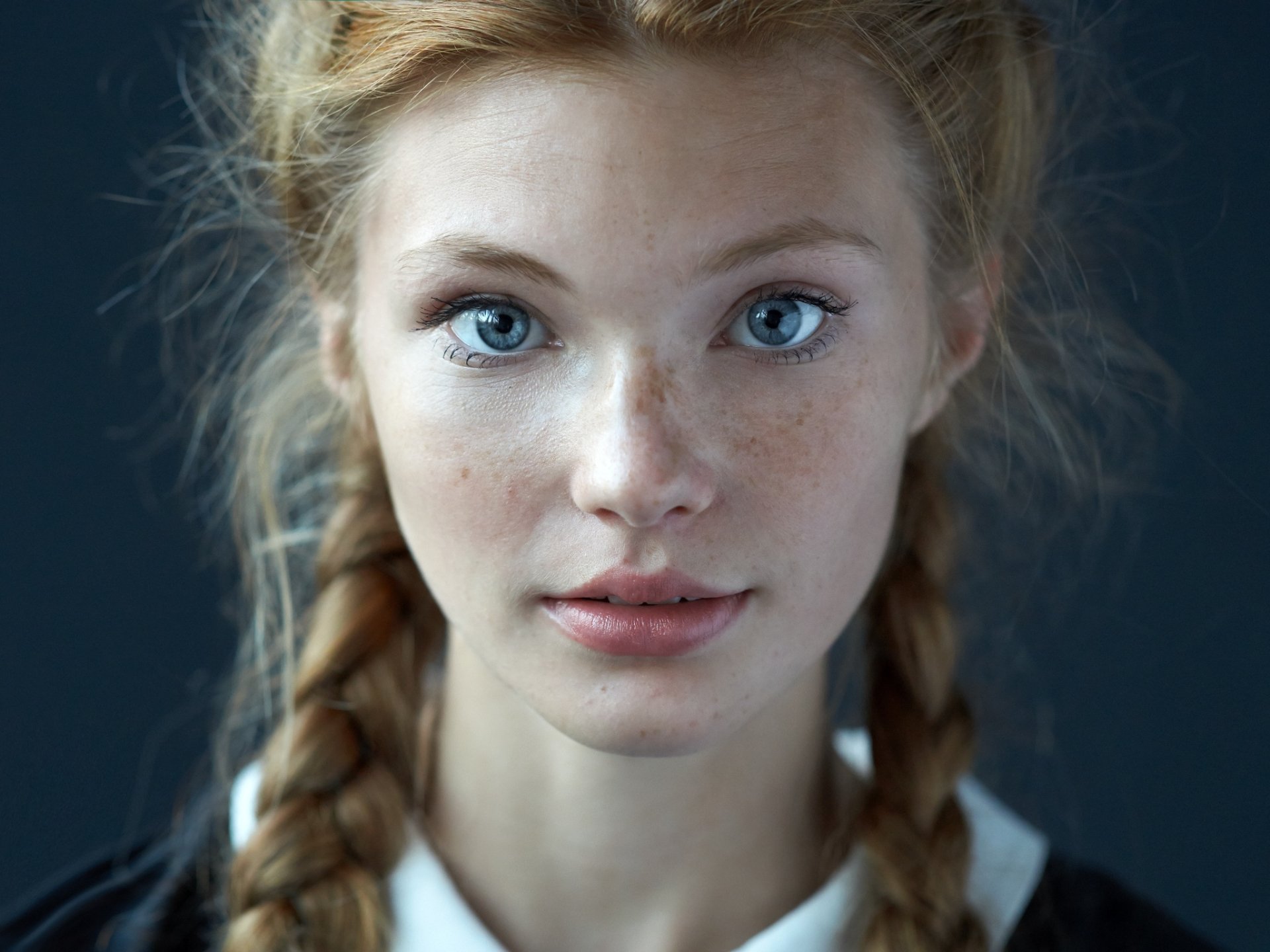 Close-up portrait of a woman model with striking blue eyes and braided hair, captured in high definition as a PC desktop wallpaper and background.