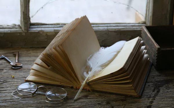 A 4K Ultra HD desktop wallpaper featuring an open book with a white feather laid inside, resting on a rustic wooden table next to round glasses by a window.