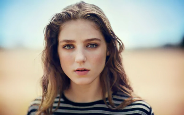 A close-up of singer Birdy, featuring her with wavy hair and intense eyes, set against a softly blurred outdoor background. A vibrant 4K Ultra HD wallpaper celebrating her music.