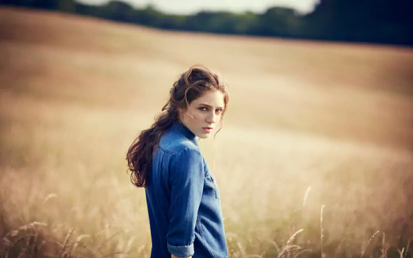 A serene image of Birdy, the English singer, captured in a golden field, exuding a contemplative mood. This 4K Ultra HD wallpaper beautifully highlights her artistic essence.