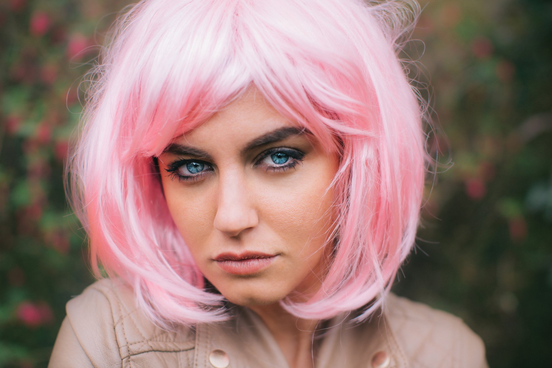 A model with striking blue eyes and a pink wig stares intently at the camera, creating an engaging and dynamic 4K Ultra HD desktop wallpaper.