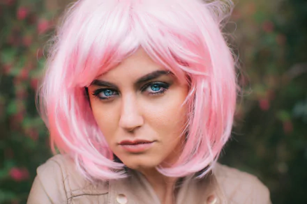 A model with striking blue eyes and a pink wig stares intently at the camera, creating an engaging and dynamic 4K Ultra HD desktop wallpaper.