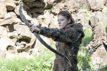 Rose Leslie as Ygritte from Game of Thrones, poised with a bow, surrounded by a natural landscape. This striking 4K Ultra HD wallpaper captures her fierce spirit from the TV show.