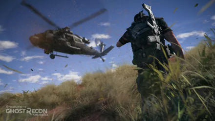 A soldier from Tom Clancy’s Ghost Recon Wildlands maneuvers through tall grass as a helicopter flies overhead, set against a vibrant blue sky, creating a dynamic HD desktop wallpaper.