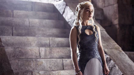 A high-definition desktop wallpaper featuring Emilia Clarke as Daenerys Targaryen from the TV show Game of Thrones, showcasing her in a medieval-style outfit standing by stone steps.