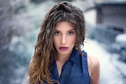 A brunette woman with brown eyes and bold lipstick stands confidently in the snow, captured in a striking HD desktop wallpaper.