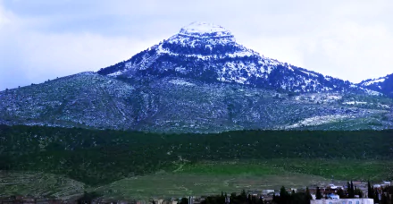 Snow-capped Tebessa Mountains rise above dense forests in Algeria's Amazigh Mountain range, captured in this HD landscape photography.