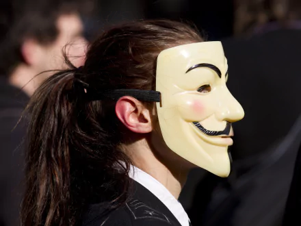 HD desktop wallpaper featuring a close-up of a person wearing a Guy Fawkes mask, embodying the theme of anonymity in technology.