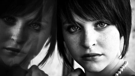 HD desktop wallpaper featuring a close-up black-and-white portrait of a woman’s face with intense eyes and short dark hair.