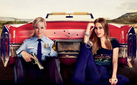 2K Quad HD desktop wallpaper of Hot Pursuit movie scene: two female leads seated against a red convertible—one in police uniform with a gun, the other casually dressed, open landscape background.