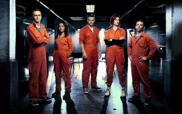 2K Quad HD PC desktop wallpaper of British sci-fi TV show Misfits: five young adults in orange jumpsuits standing in a dim, industrial room.