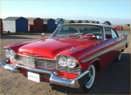 HD PC desktop wallpaper: red Plymouth Fury vehicle parked by seaside beach huts, showcasing classic chrome trim, dual headlamps and whitewall tires.