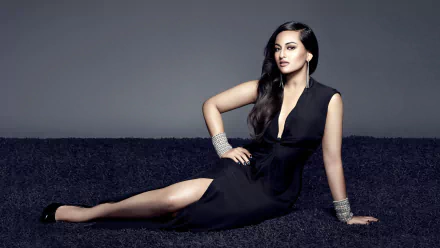 A stylish woman with long black hair, brown eyes, and a black dress reclines elegantly while wearing high heels, earrings, and a bracelet. This HD wallpaper features a confident fashion-forward pose.