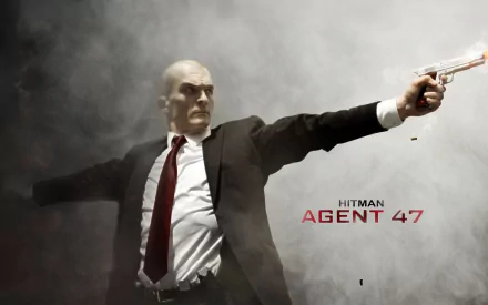HD PC desktop wallpaper featuring Hitman: Agent 47, showing the bald assassin in a suit aiming a silver pistol with smoke in the background.