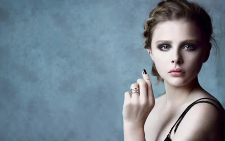 Chloë Grace Moretz poses elegantly against a textured blue background, showcasing her striking features in this HD desktop wallpaper and background.
