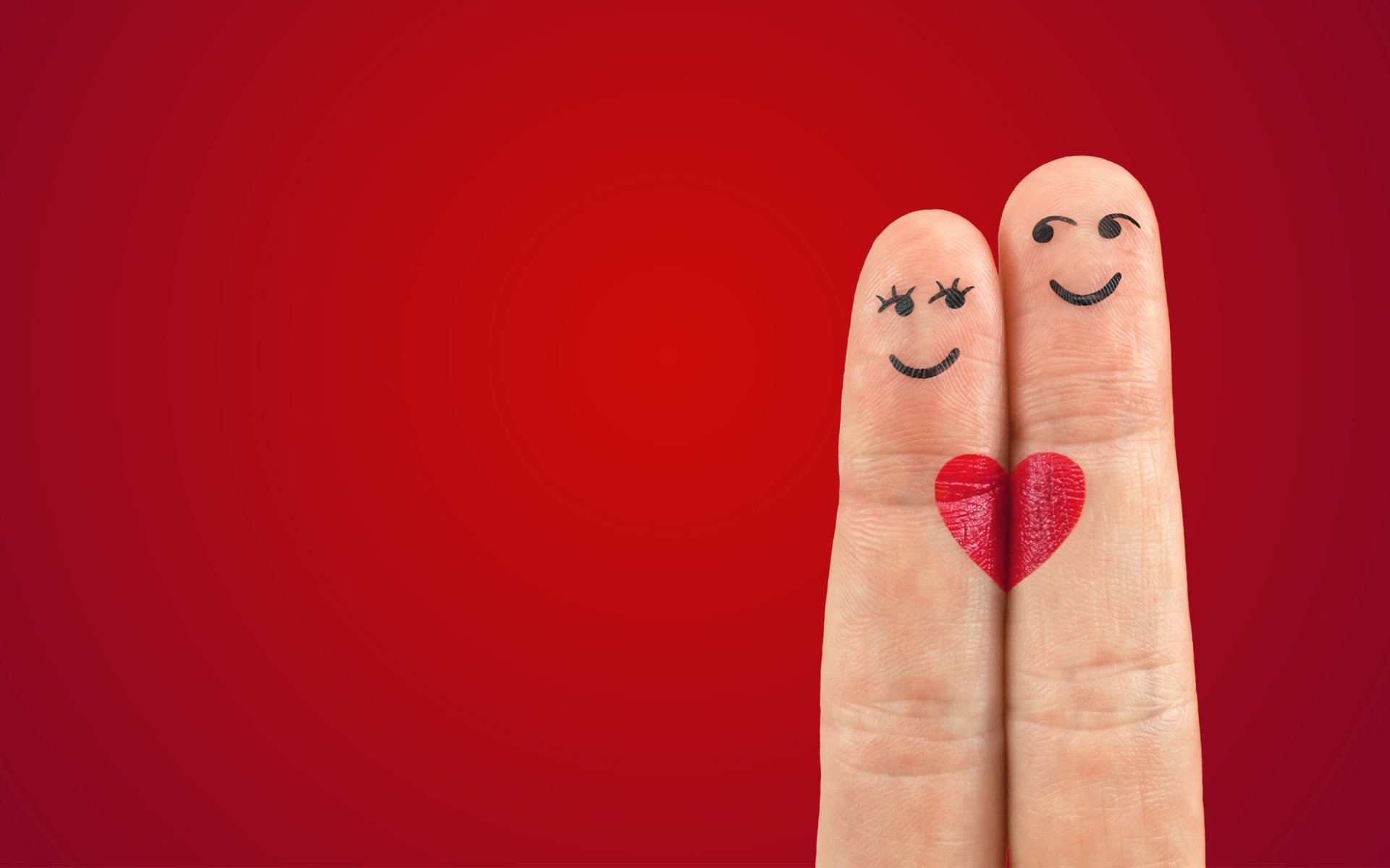 Two fingers with drawn smiley faces and a red heart between them on a red background, creating an artistic and heartfelt depiction of love. HD desktop wallpaper and background.