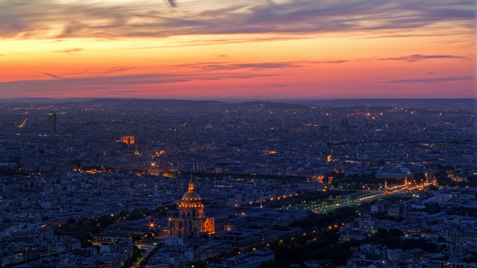 HD desktop wallpaper showcasing a panoramic view of Paris at sunset, highlighting the city's iconic man-made structures and glowing city lights.