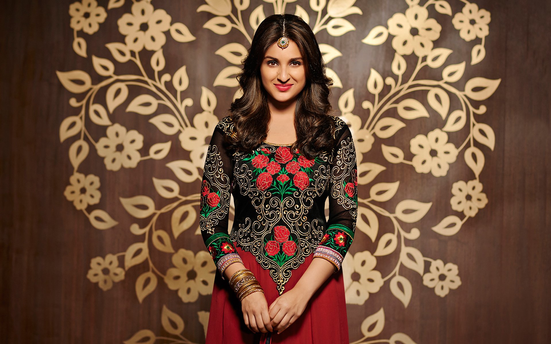 A glamorous Parineeti Chopra poses in a beautifully detailed embroidered outfit against a floral backdrop, serving as an elegant HD desktop wallpaper and background.
