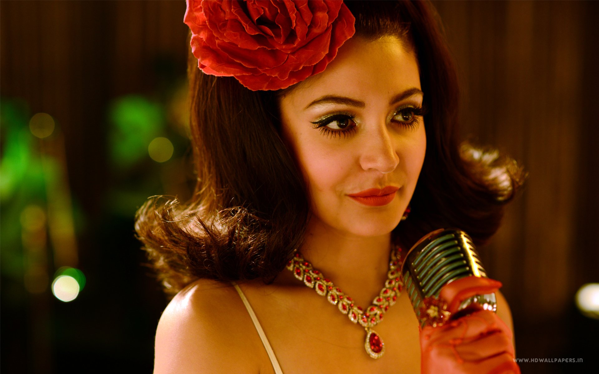 Glamorous vintage movie-style portrait of an actress with a red rose in her hair, jeweled necklace and red glove, holding a retro microphone — 2K Quad HD desktop wallpaper