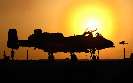 Silhouetted Fairchild Republic A-10 Thunderbolt II aircraft on runway at sunset, captured in an HD military-themed desktop wallpaper.